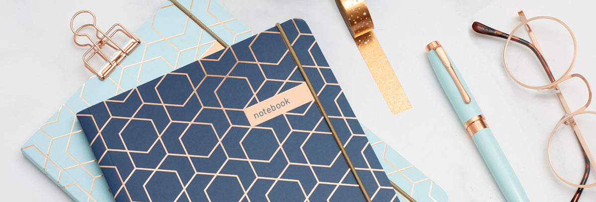 Collins Debden stationery with patterned notebooks, pen and glasses