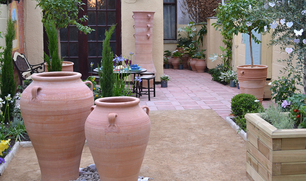 The Terracotta Pot Company large hand-thrown Cretan terracotta planters and decorative pots in a garden courtyard