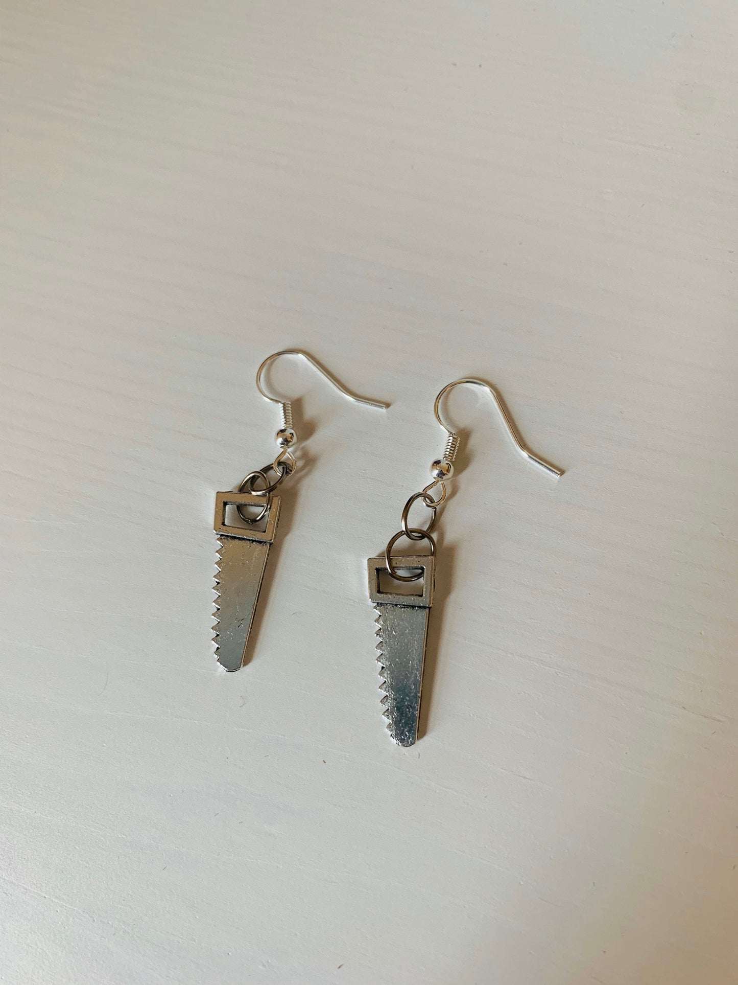 Silver hacksaw or saw earrings.