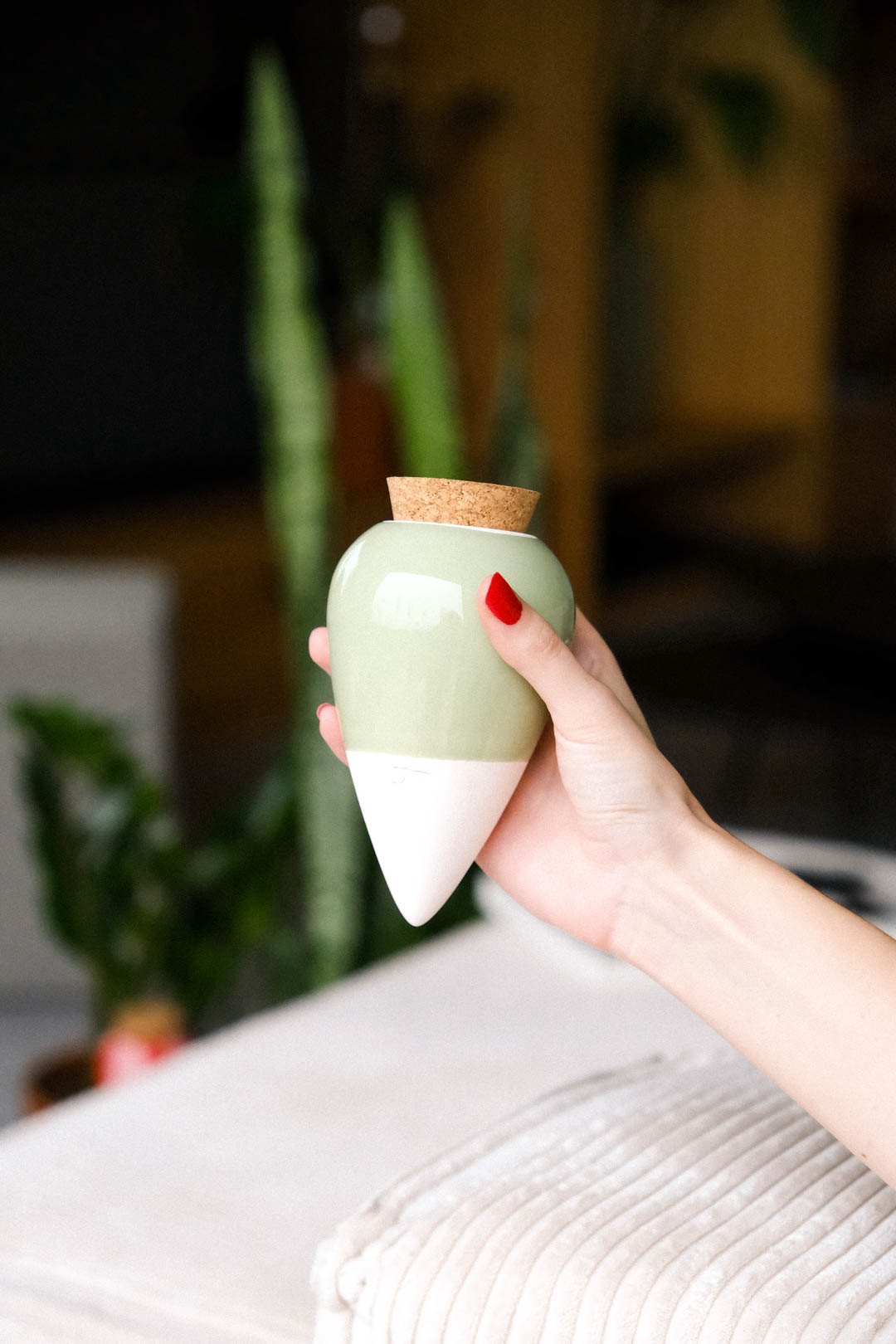 Sage green Pepin Olla held in the hand in a bright living room