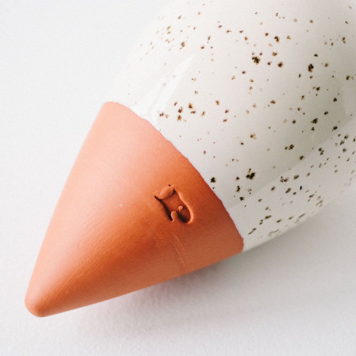 Close-up of the speckled white glaze and terracotta tip of the Pepin Olla