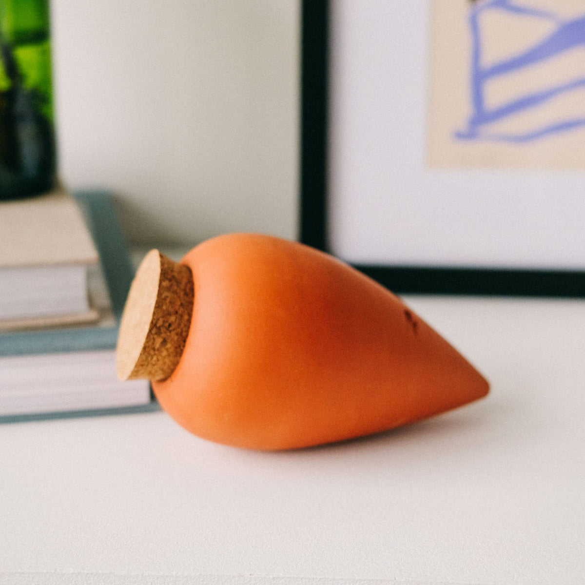 Natural terracotta Pepin Olla with cork stopper lying on a white shelf
