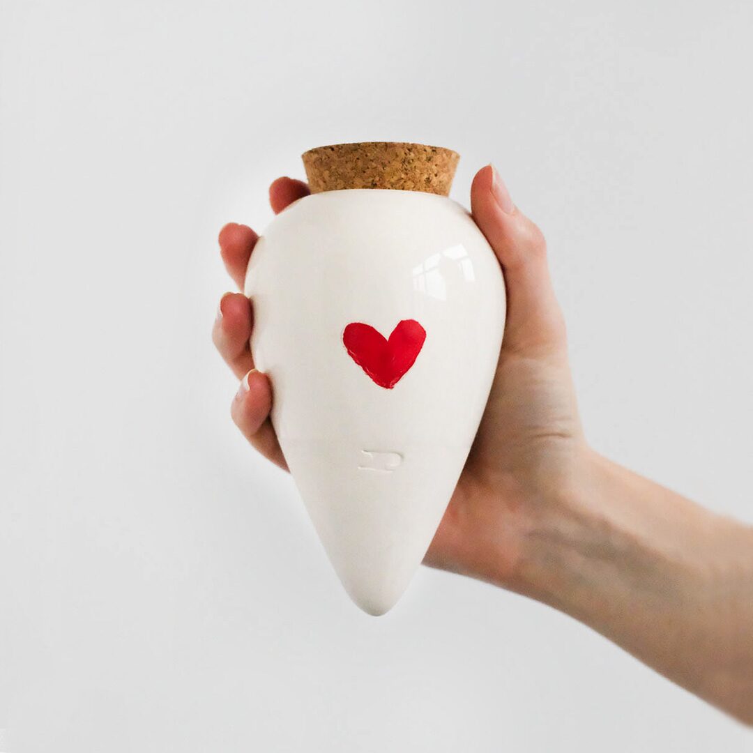 Pepin Olla in white glaze with a hand-painted red heart, held in the hand