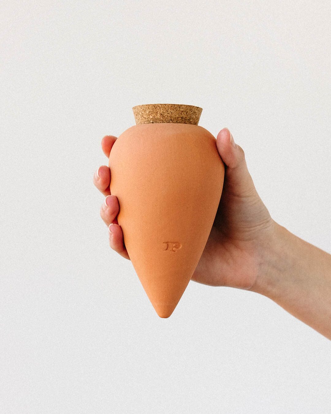 Pepin Olla in natural terracotta with cork stopper, held in the hand
